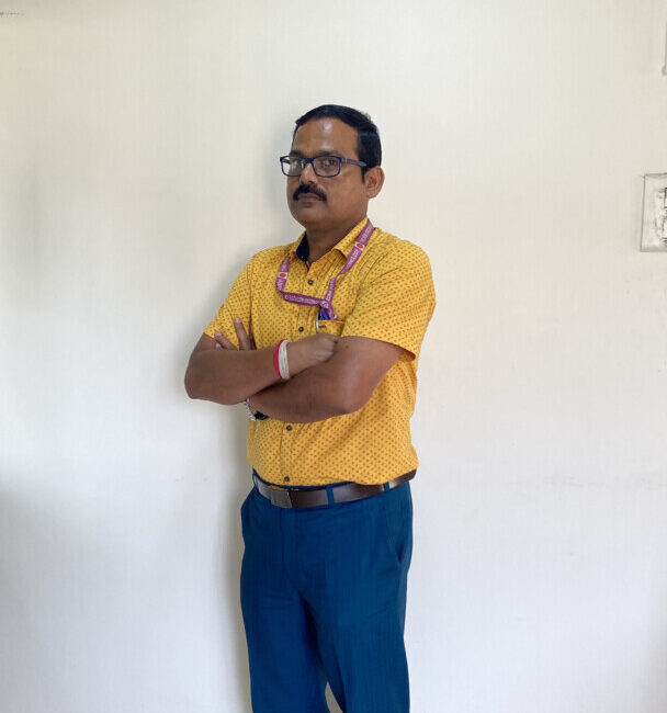 Man in yellow shirt standing indoors