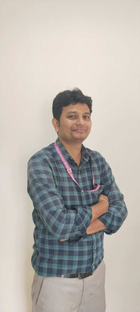 Man in plaid shirt with crossed arms smiling