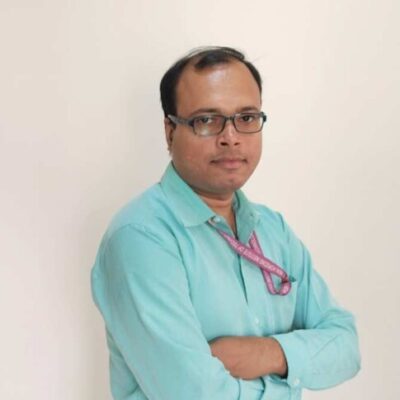 Man in turquoise shirt with arms crossed.