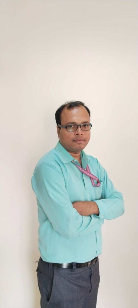 Man in turquoise shirt with arms crossed.