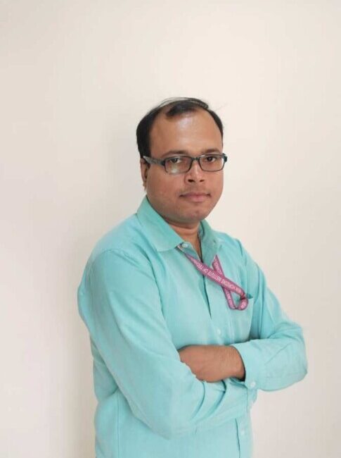 Man in turquoise shirt with arms crossed.