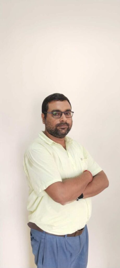 Person with glasses wearing light shirt and blue pants