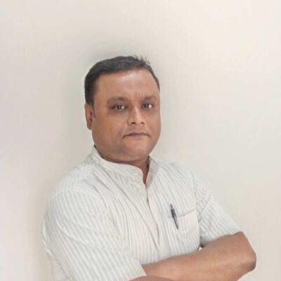 Man with crossed arms poses against a light wall