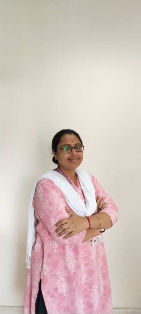 Woman in pink outfit with folded arms.