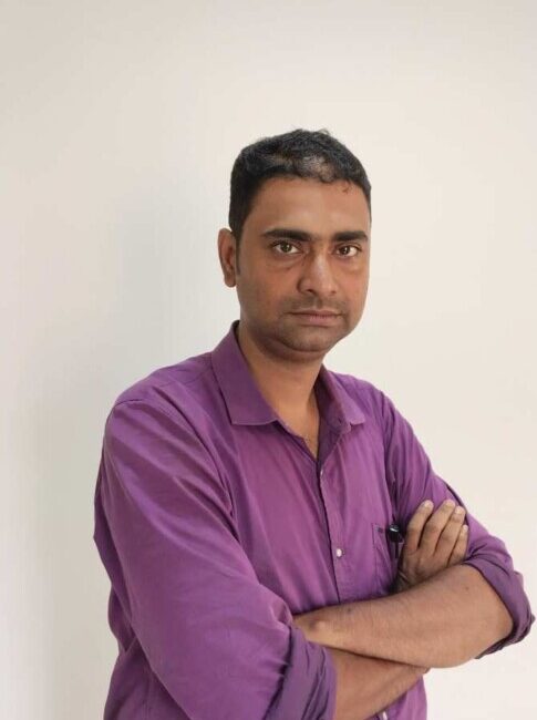 Man in purple shirt with arms crossed.