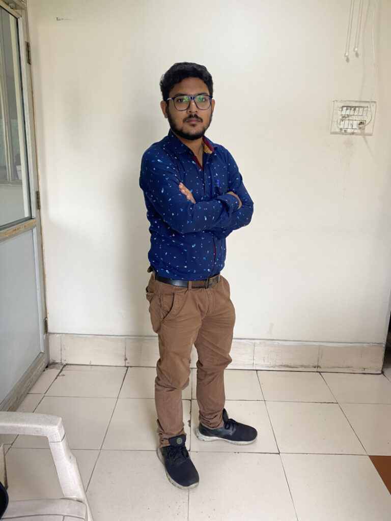 Man standing confidently with arms crossed indoors.