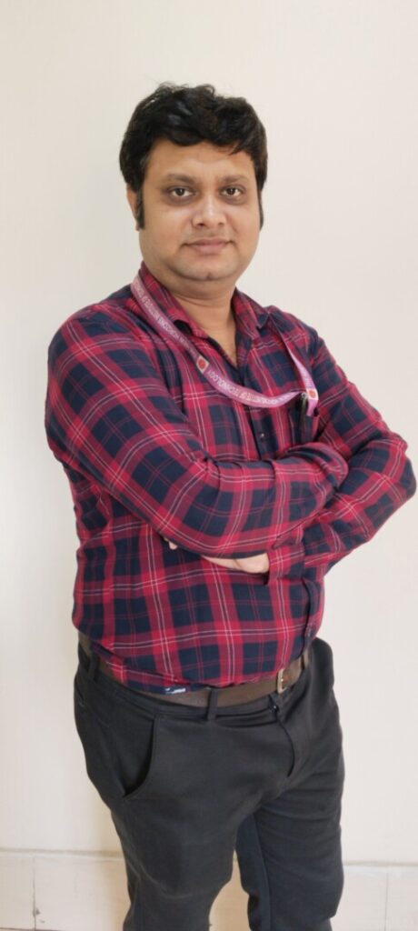 Person in plaid shirt, arms crossed, standing confidently.