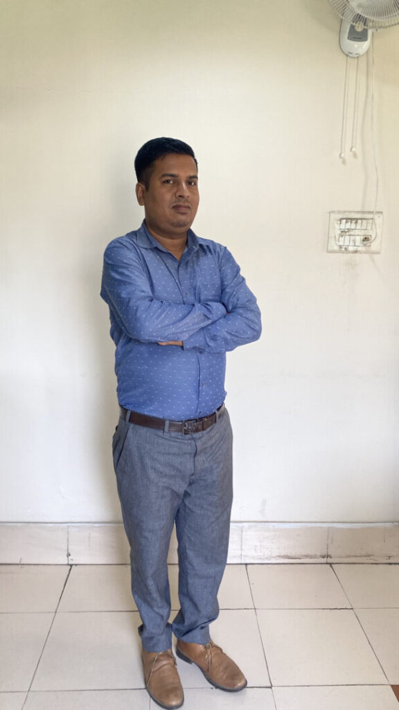 Man in blue shirt standing with arms crossed