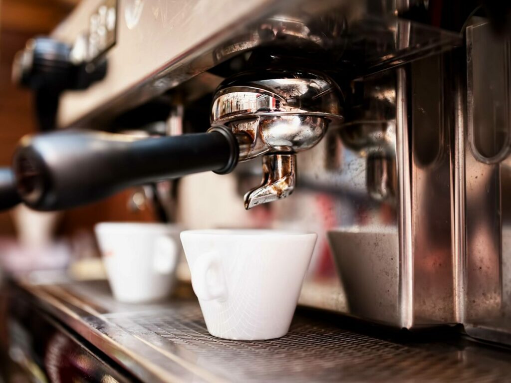 Espresso machine brewing coffee into cup.